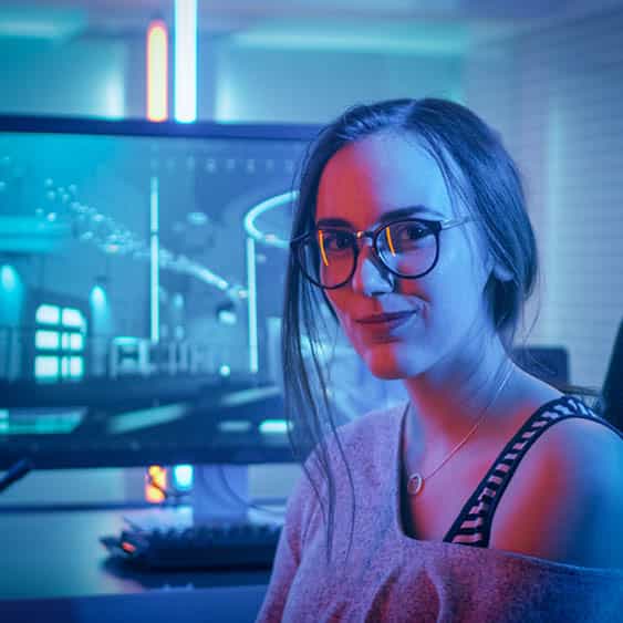 Frau in einem blau beleuchtendem Zimmer vor einem Computer